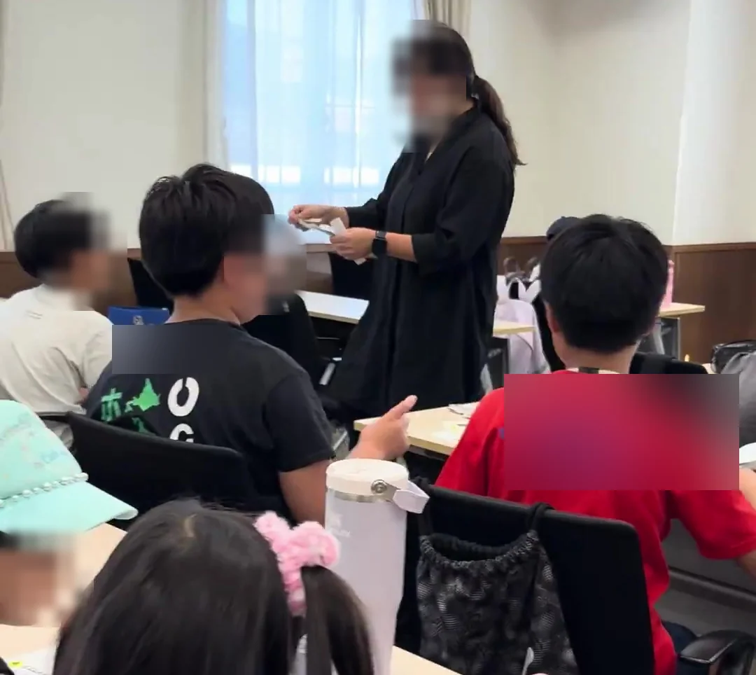 机を囲んでお店づくりについて考える活動風景。顔が判別できる部分と衣服の文字は加工済み